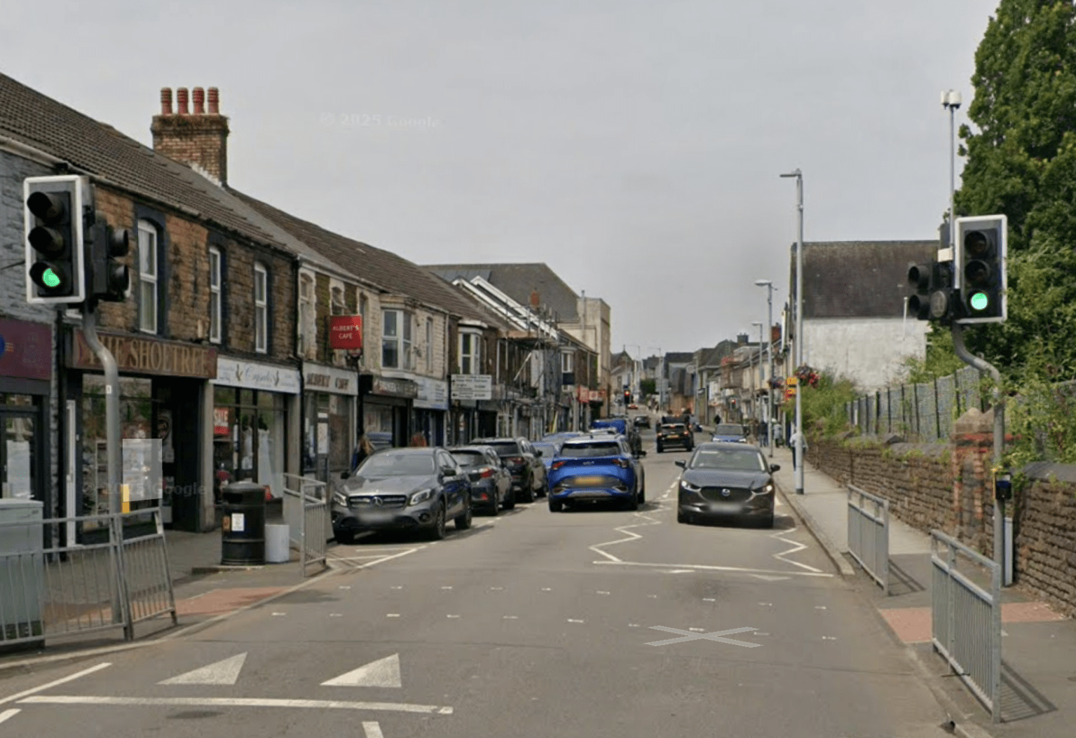 Street view of Gorseinon town centre with shops, traffic and pedestrians.