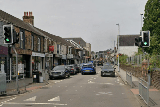 Street view of Gorseinon town centre with shops, traffic and pedestrians.