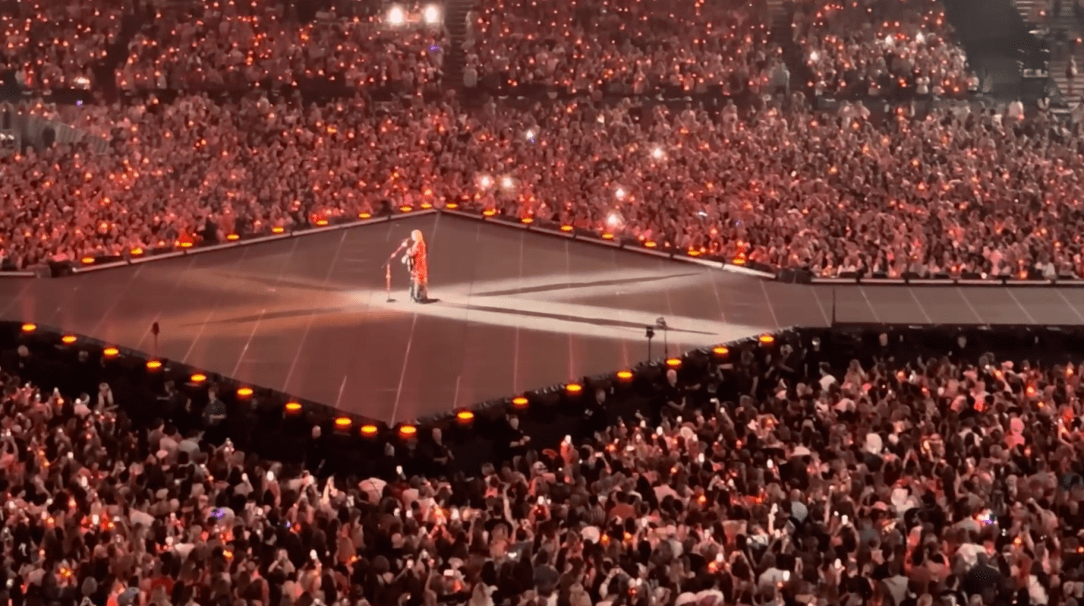 Taylor Swift performing on a central stage at the Principality Stadium in Cardiff during the 2024 Eras Tour.