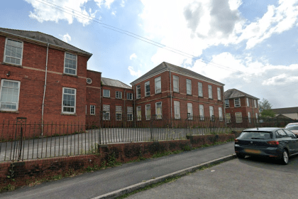 Front view of the former Stebonheath School in Llanelli, showing the red‑brick building, railings and parked cars.