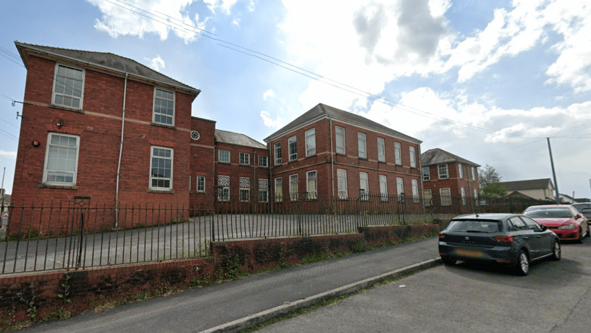 Front view of the former Stebonheath School in Llanelli, showing the red‑brick building, railings and parked cars.