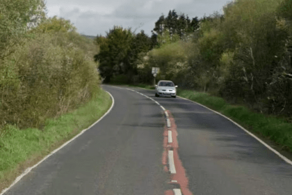 The A484 road between Pembrey and Kidwelly showing a tree-lined rural road with white and red road markings