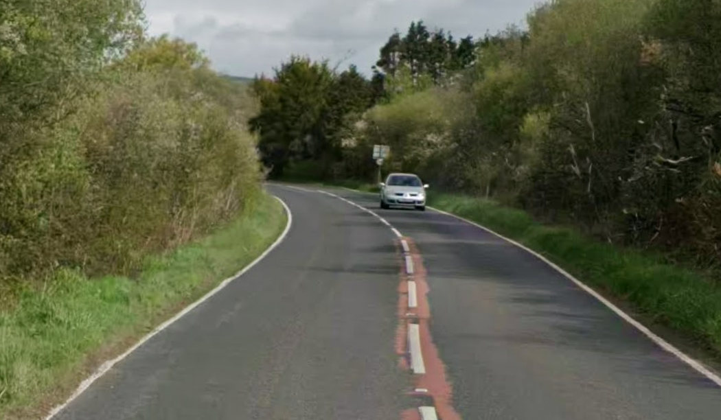 The A484 road between Pembrey and Kidwelly showing a tree-lined rural road with white and red road markings