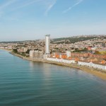 Coastal view of Swansea showing the beach, seafront buildings, the Meridian Tower and the city rising into the hills behind.