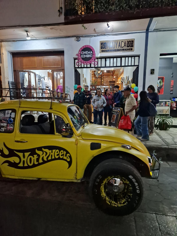 Yellow customised VW Beetle parked outside Cinema Kinoki at night.