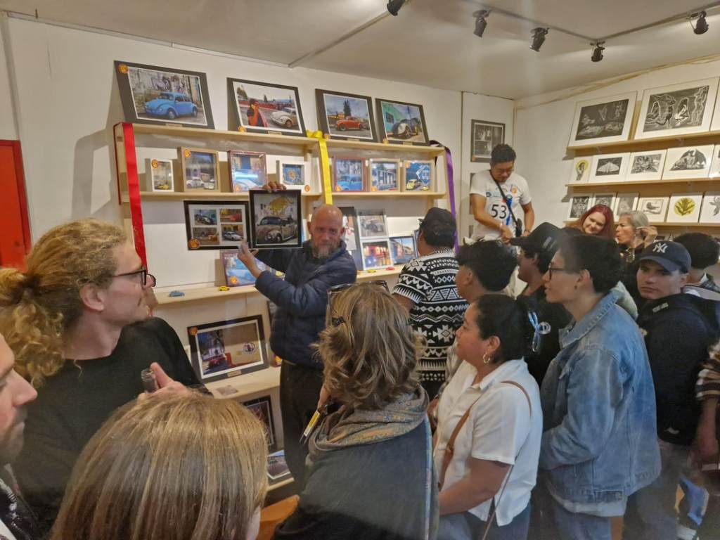 People viewing framed VW Beetle photographs at an exhibition.