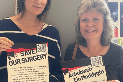 Clare Treharne and Jane Nicholas holding bilingual Save Our Surgery posters in Pontyates.
