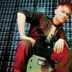 LOOK MUM NO COMPUTER sitting on vintage electronic equipment in a studio filled with illuminated components, photographed ahead of representing the UK at Eurovision 2026.