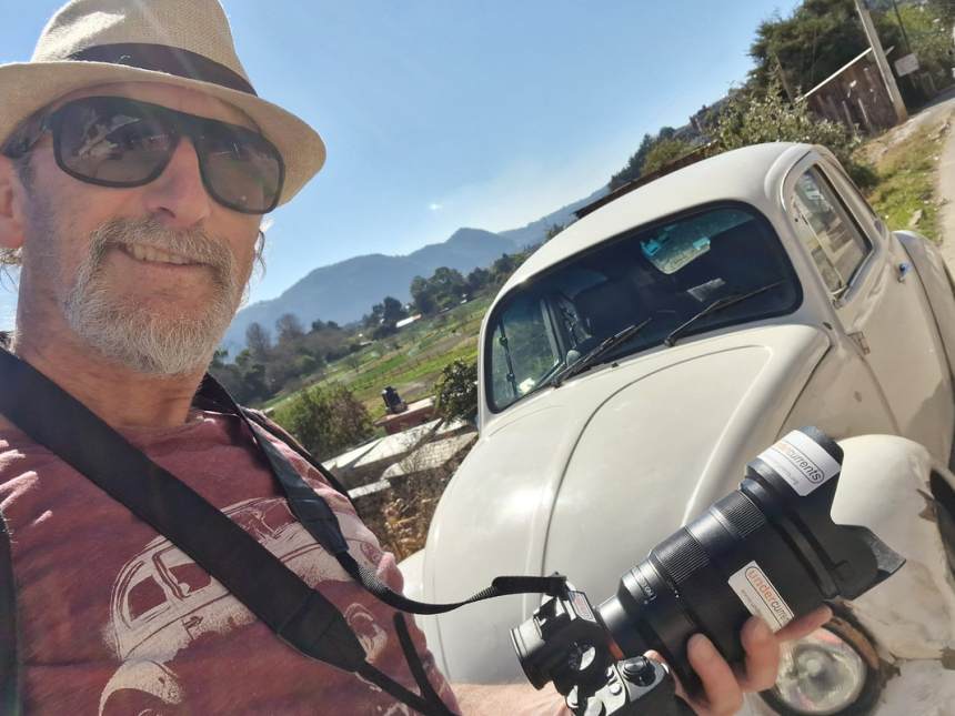 Paul O’Connor taking a photo in front of a vintage VW Beetle in the Mexican countryside.