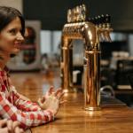 woman in check shirt waiting at bar