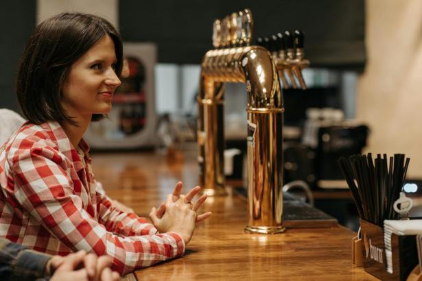 woman in check shirt waiting at bar
