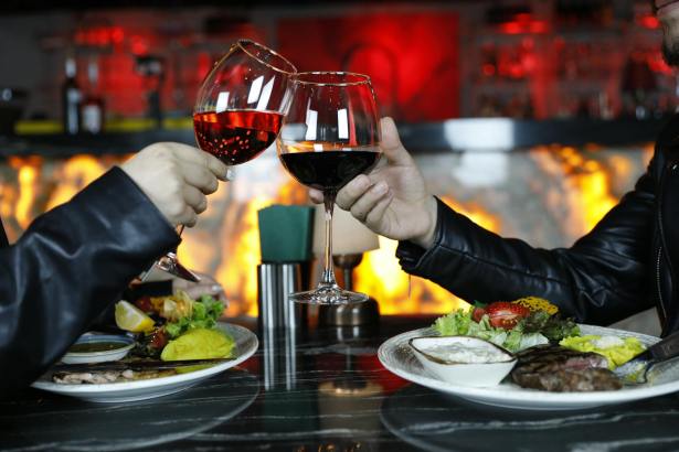 person holding clear wine glass with red wine