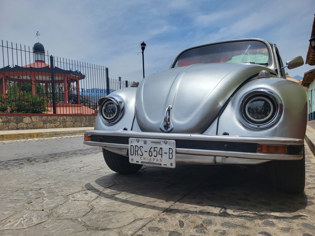 Silver VW Beetle parked on a cobbled street in Mexico.