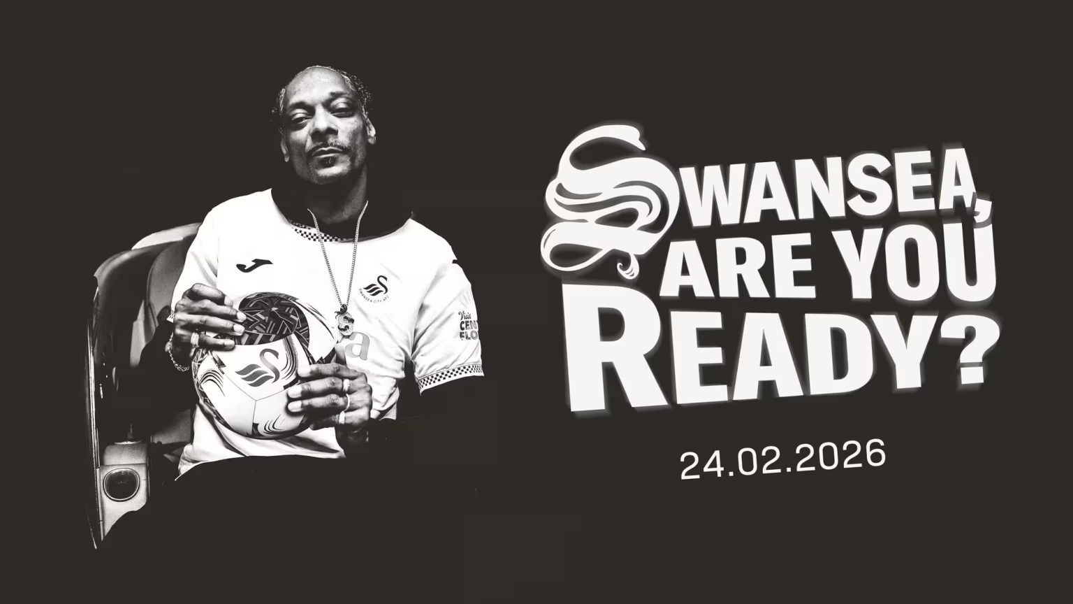 Cropped black‑and‑white image of Snoop Dogg wearing a Swansea City shirt and holding a football with the club badge.