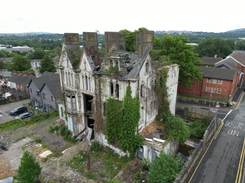 Aerial view of Danbert House in Morriston, Swansea, showing the dilapidated Victorian building with a damaged roof, broken windows and overgrown vegetation surrounding the structure.