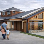 Artist’s impression showing a family walking towards a redesigned timber-clad entrance building at WWT Llanelli Wetland Centre with improved access and modern facilities.