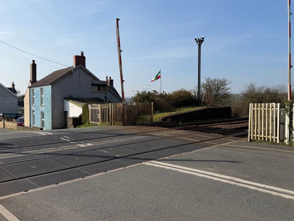 Railway level crossing in St Clears showing tracks and surrounding road where a station once operated.