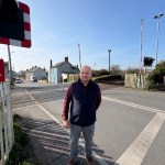 Carl Peters-Bond stands at a level crossing in St Clears near the proposed site of the reopened railway station.