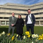 Torsten Bell MP, Welsh Secretary Jo Stevens and Swansea Council leader Rob Stewart stand outside Swansea Civic Centre with daffodils in the foreground after £20 million funding announcement.