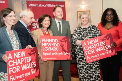 A group of six people, including Eluned Morgan, Rob Stewart, and Mike Hedges, standing together on a stage smiling for a professional group photo.