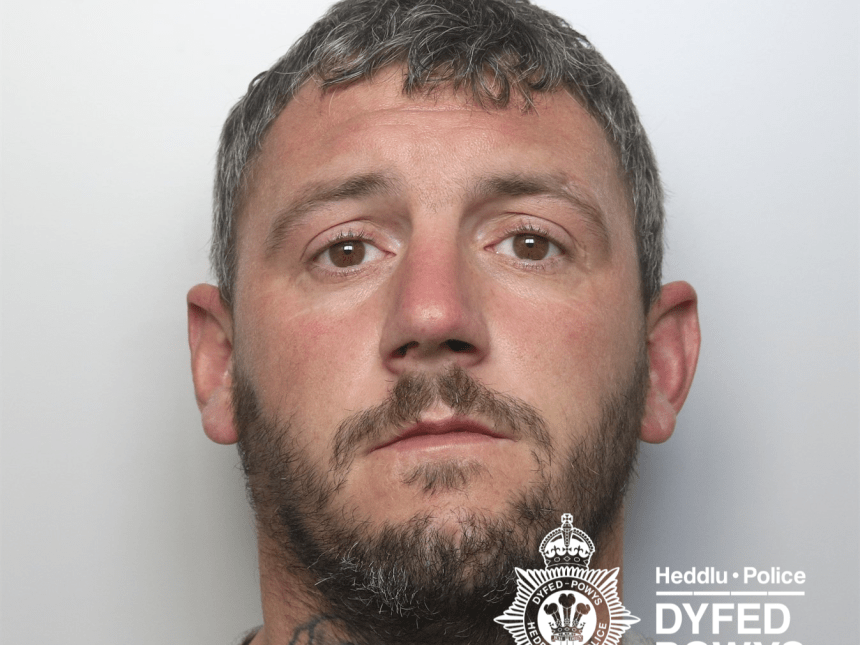A police custody photograph of Leon Kidner, a man with short dark hair, a beard, and a large tattoo of roses on his neck.