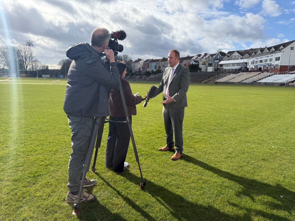 Swansea Council leader being interviewed by media on rugby pitch at St Helens Swansea during Ospreys announcement