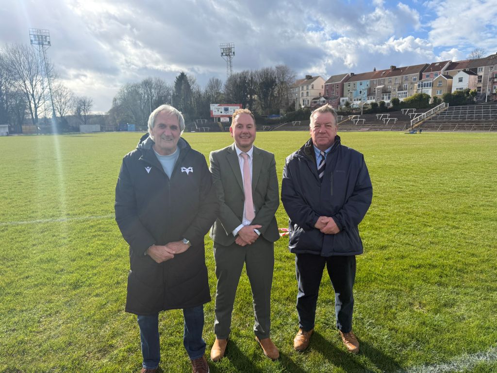 Three men standing on rugby pitch at St Helens Swansea during announcement of council and Ospreys partnership
