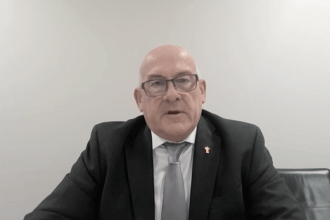 WRU Chair Richard Collier-Keywood, wearing a dark suit and grey tie with a gold WRU pin badge, speaks via video link to the Senedd committee.