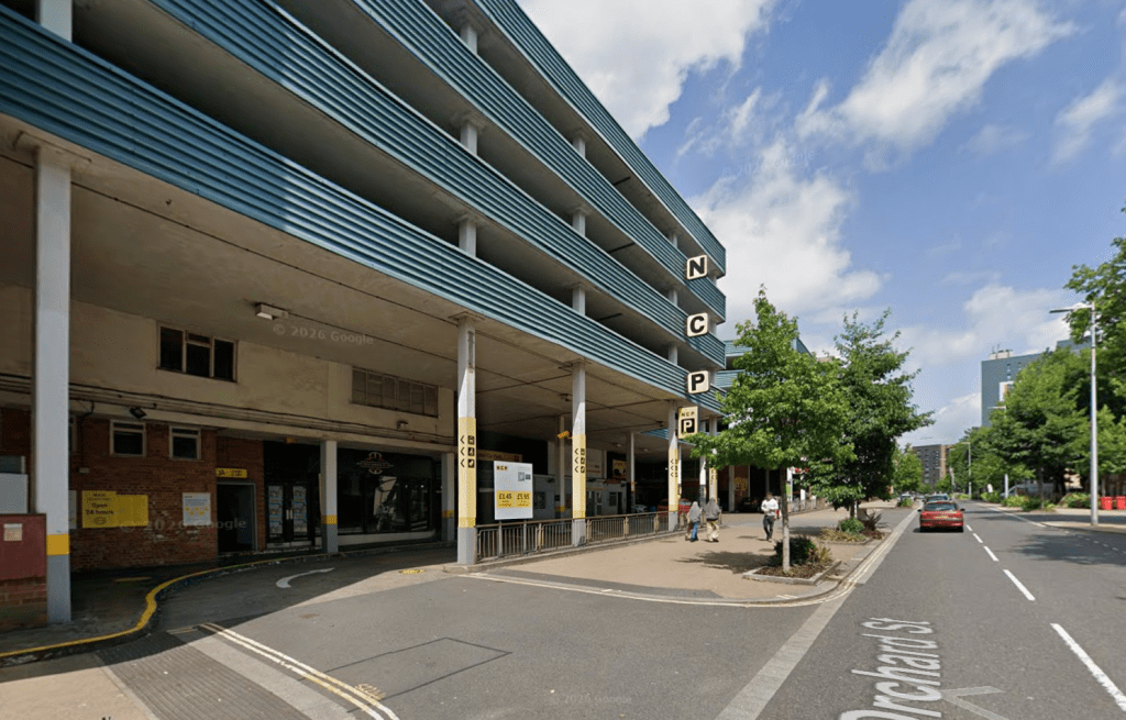 Front view of NCP Swansea Orchard Street car park building with entrance signage and surrounding trees.