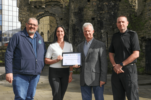 Four representatives from Swansea BID, Swansea Against Business Crime and South Wales Police holding a national safety accreditation certificate in Swansea city centre.