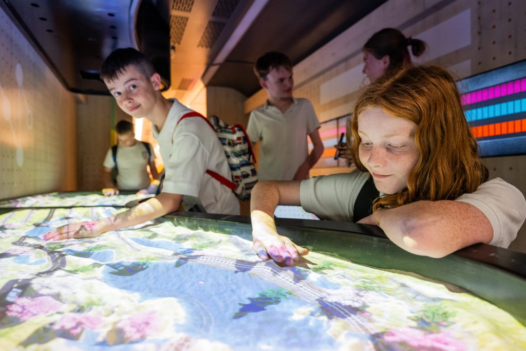 Children exploring a large interactive digital map display inside the Inspiration exhibition train.