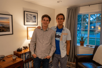 A portrait of two men, Tobias and Marc, standing in their living room. One has his arm around the other, and they are both smiling at the camera.