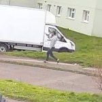 A CCTV screengrab showing a man in a grey top and dark trousers running along a pavement in a residential street, holding an object that appears to be a handgun.