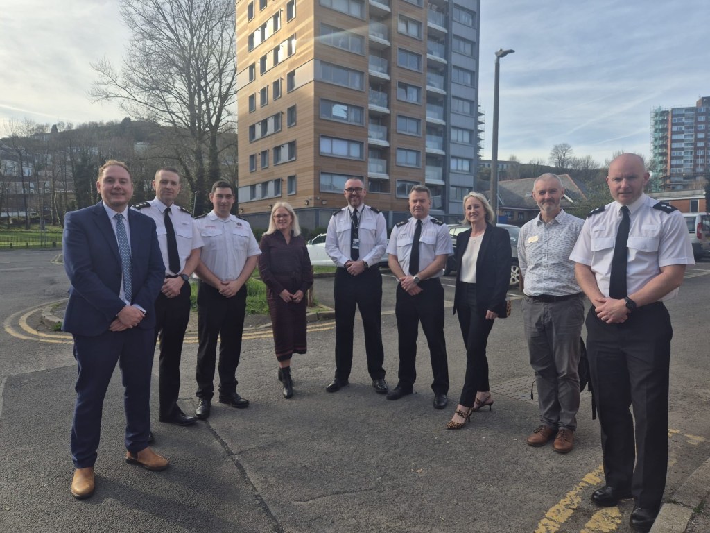 Police officers, council officials and partners standing together in front of the Matthew Street tower blocks in Dyfatty, Swansea, at the launch of Clear, Hold, Build