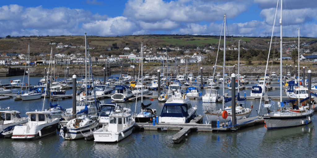 Boats moored at Burry Port marina with town and hills in background Carmarthenshire