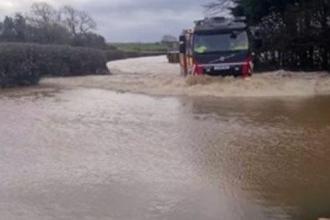 Vehicle driving through deep floodwater on the A4118 near Scurlage in Gower during severe flooding.