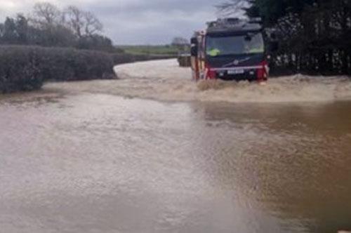 Vehicle driving through deep floodwater on the A4118 near Scurlage in Gower during severe flooding.