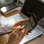 person using a calculator and a laptop