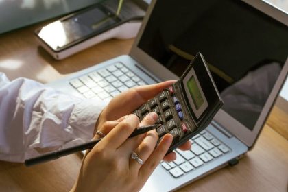 person using a calculator and a laptop
