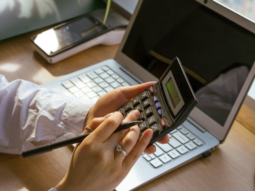person using a calculator and a laptop