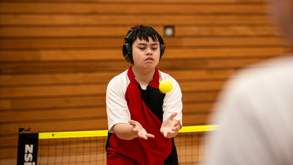 Young participant catching a ball during an indoor inclusive sports session.