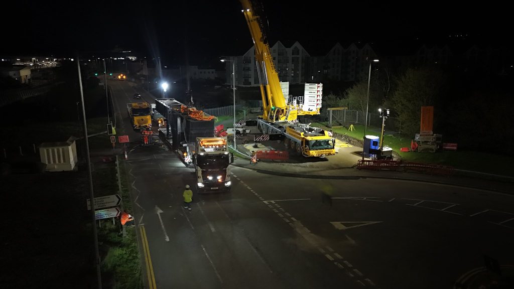 Aerial night shot of the Swansea Bascule Bridge being transported through the city on a heavy haulage vehicle with crane support