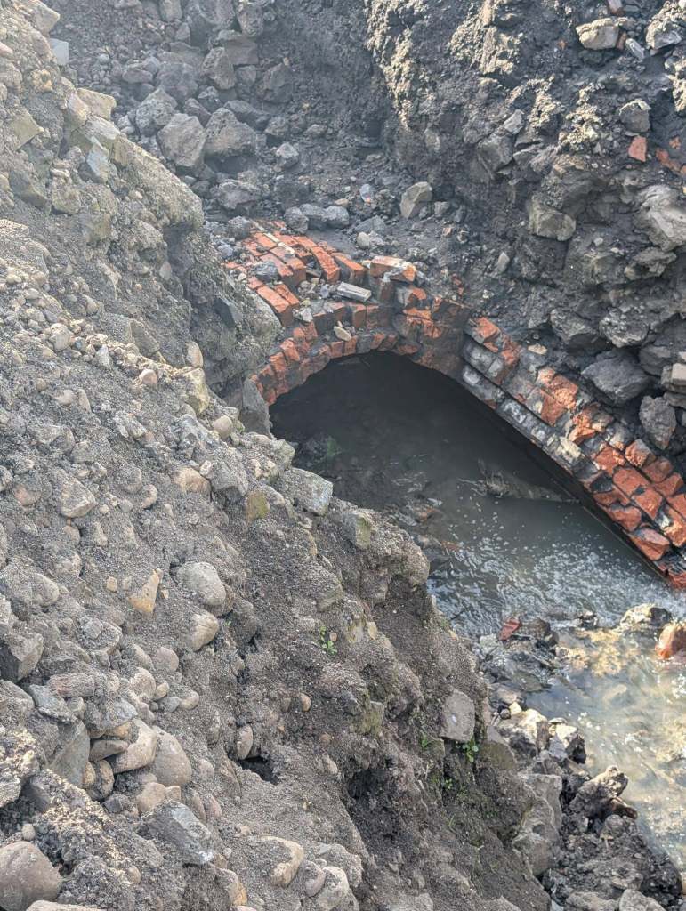 Victorian brick arch culvert exposed at the Cwmfelin Club site in Cwmbwrla, Swansea, with water flowing below
