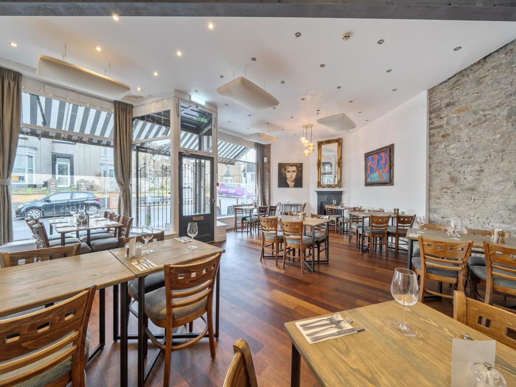 The interior of Truffle restaurant in Uplands, Swansea, showing the dining room with wooden floors, exposed stone wall and large front windows