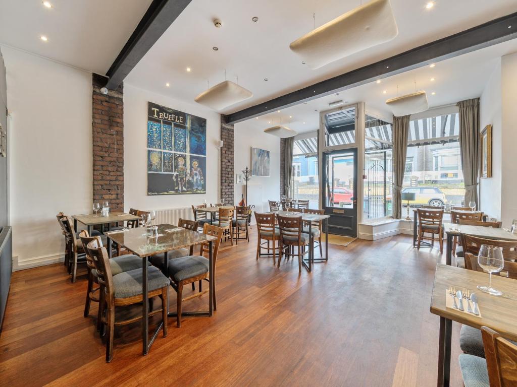 A wider view of the dining room at Truffle restaurant in Uplands, Swansea, showing exposed brickwork, artwork and the restaurant's frontage