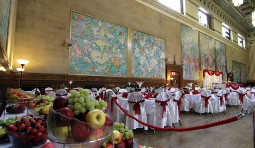 he main hall at Brangwyn Hall in Swansea set for a wedding reception, with the famous Frank Brangwyn panels lining the walls and tables dressed in white and red