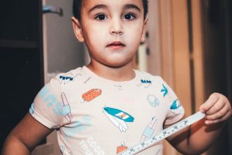 young child playing indoors with measuring tape
