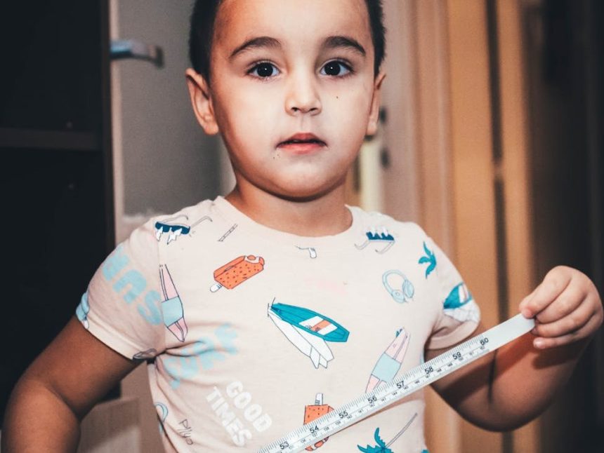 young child playing indoors with measuring tape