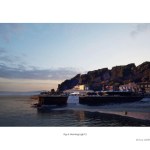 A computer-generated dawn view of the proposed Knab Rock development viewed from the sea, with golden morning light catching the cliff face, the new sporting centre building partially illuminated and the Mumbles village rooftops in soft silhouette