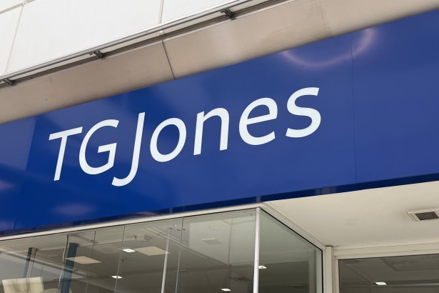 Close-up of a large blue TGJones shop fascia above a glass shopfront, photographed from below at an angle.